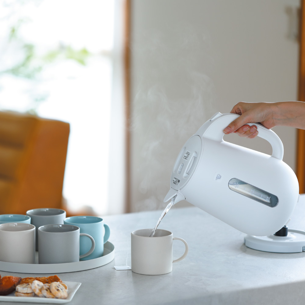 ผู้หญิงถือกาต้มน้ำร้อนไฟฟ้าซึ่งเป็นเครื่องใช้ไฟฟ้าภายในบ้าน