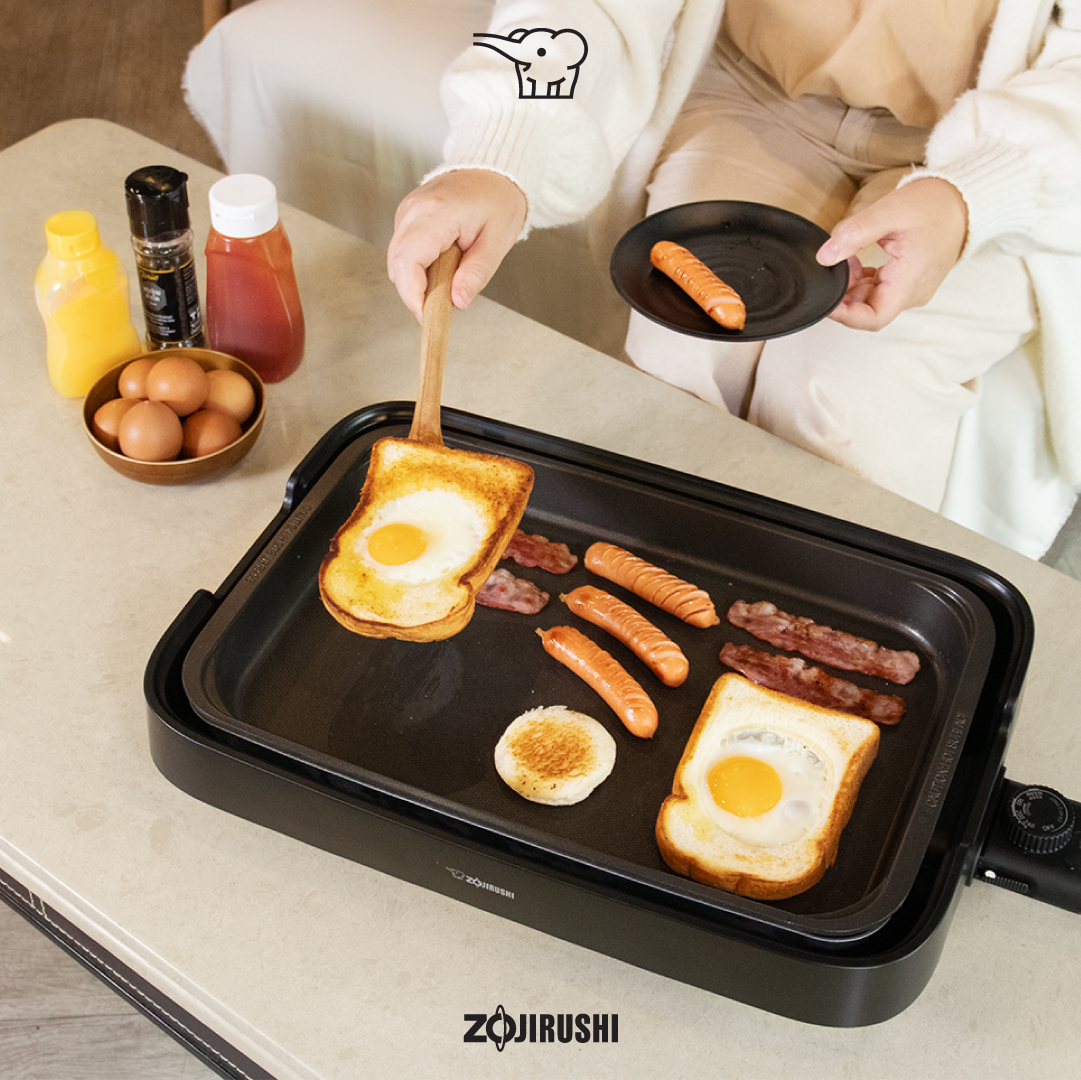 ผู้หญิงกำลังทำอาหารเช้าด้วยเตาปิ้งย่างไฟฟ้าซึ่งเป็นเครื่องใช้ไฟฟ้าภายในบ้าน